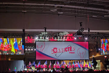 A stage with several flags and a large screen displaying "CONNECTED" in front of a crowd.