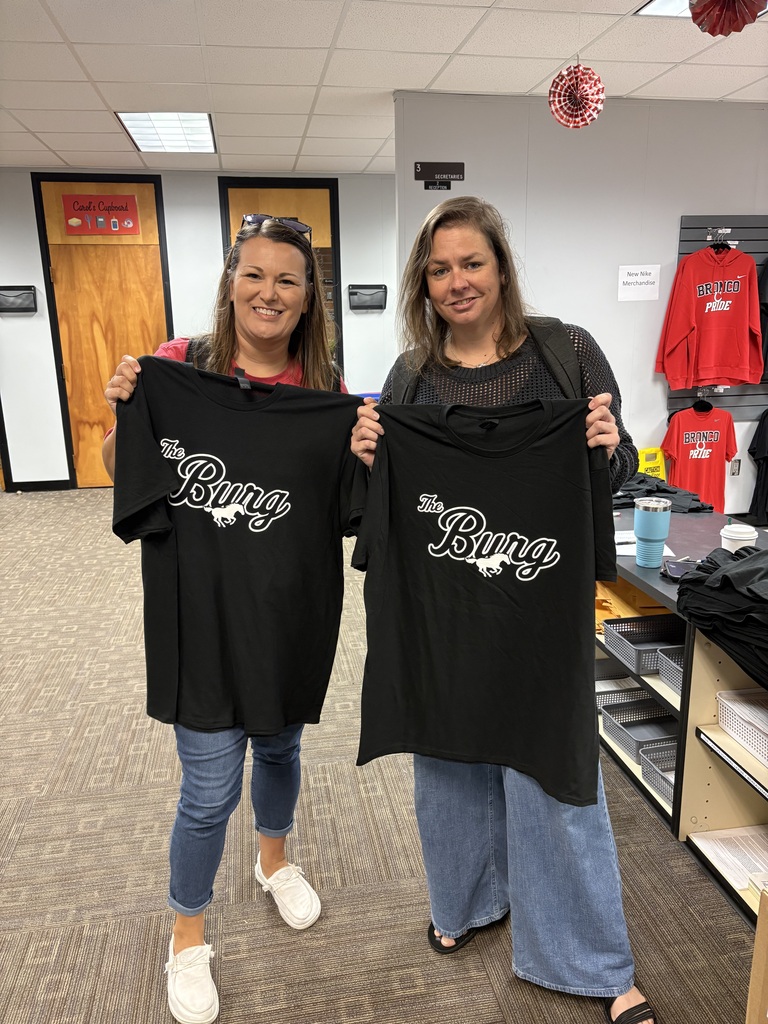 Two women holding shirts.