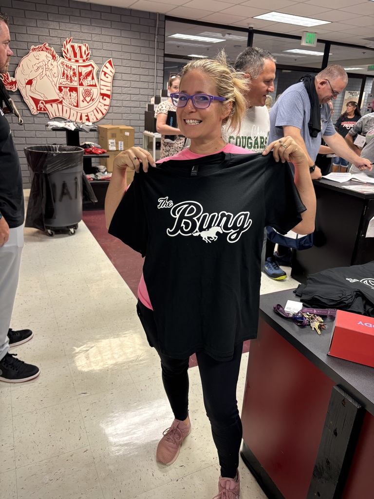 Woman holding a black shirt with the word "Bung" written in white letters, standing in a room.