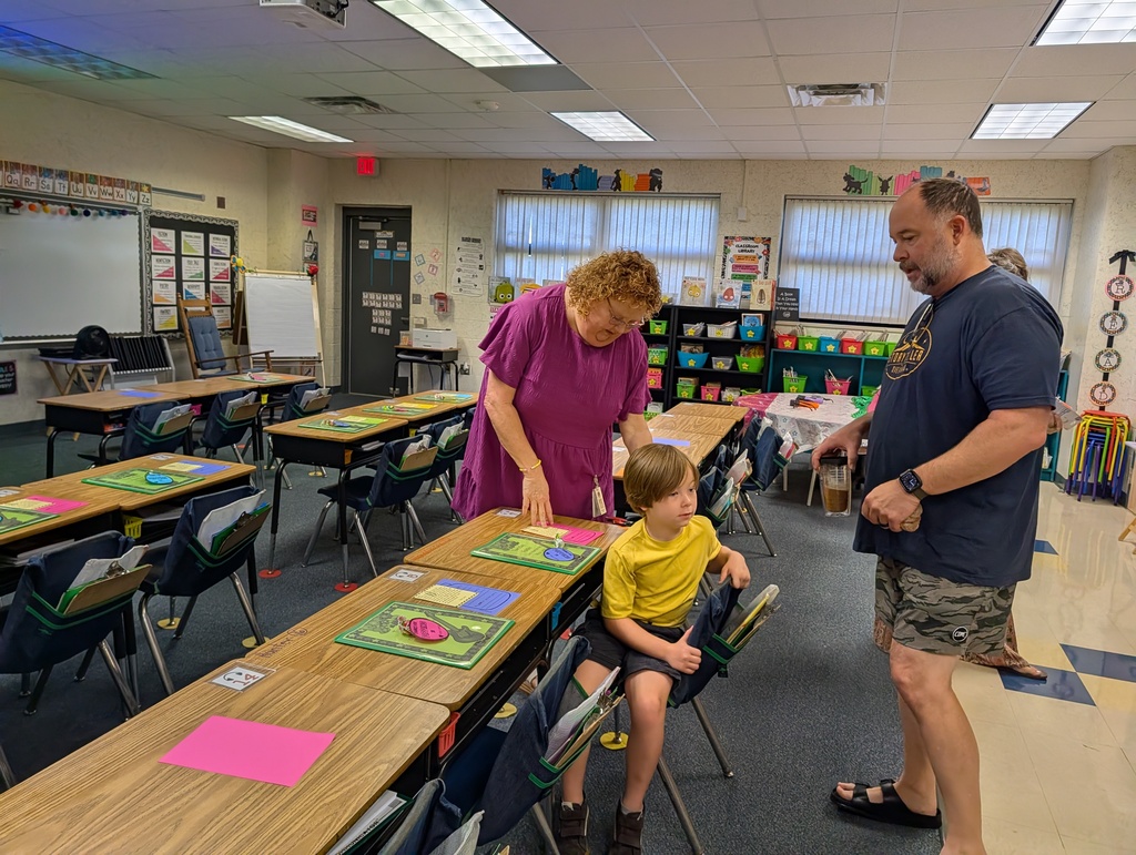 Three people in a classroom, a man in blue, a woman in purple, and a child in yellow.