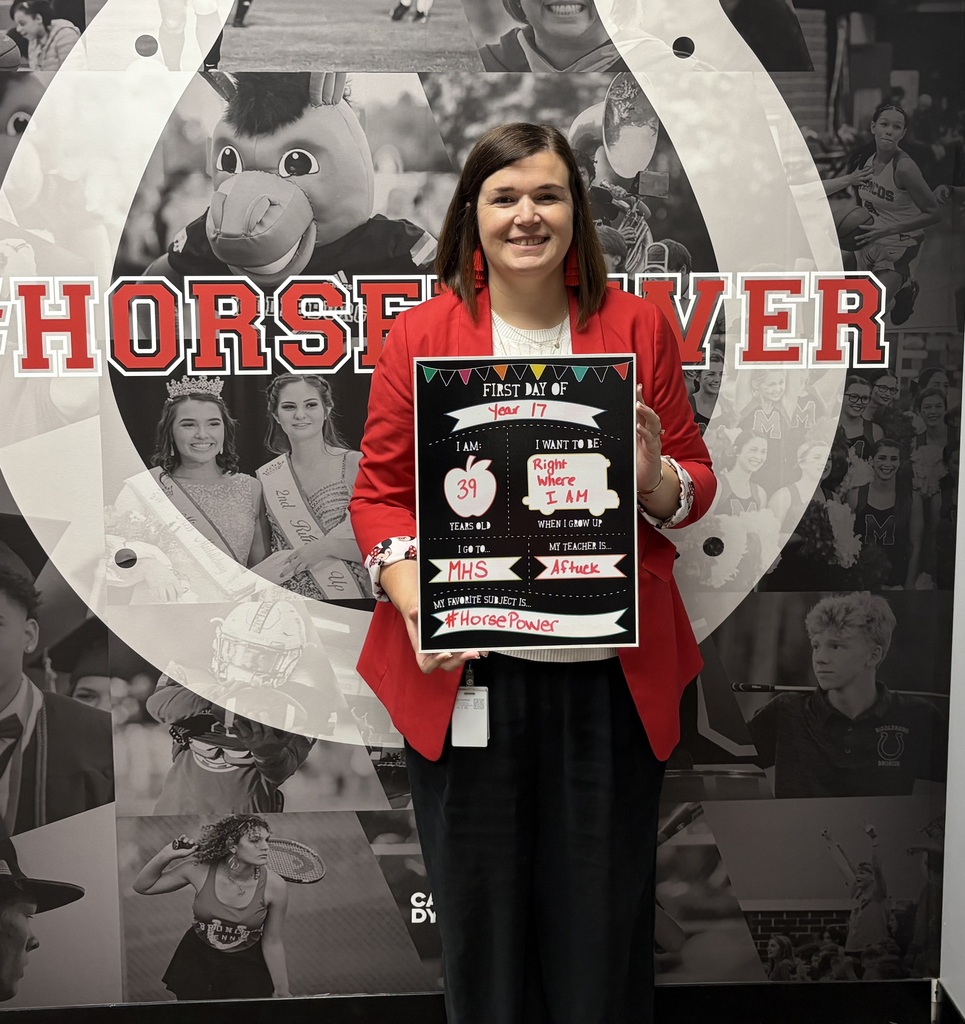 A woman in a red jacket stands in front of a large photo collage, holding an award.