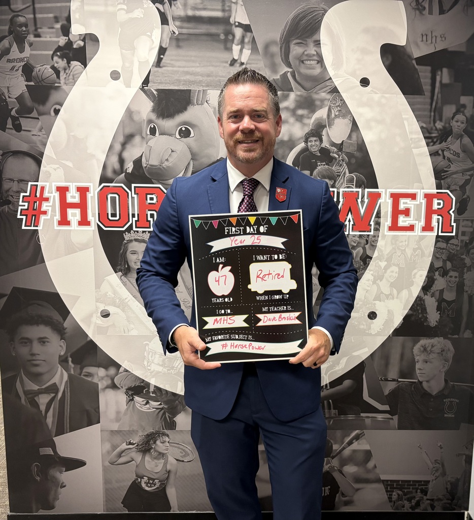 Man in a blue suit holding a plaque in front of a collage of sports team images.