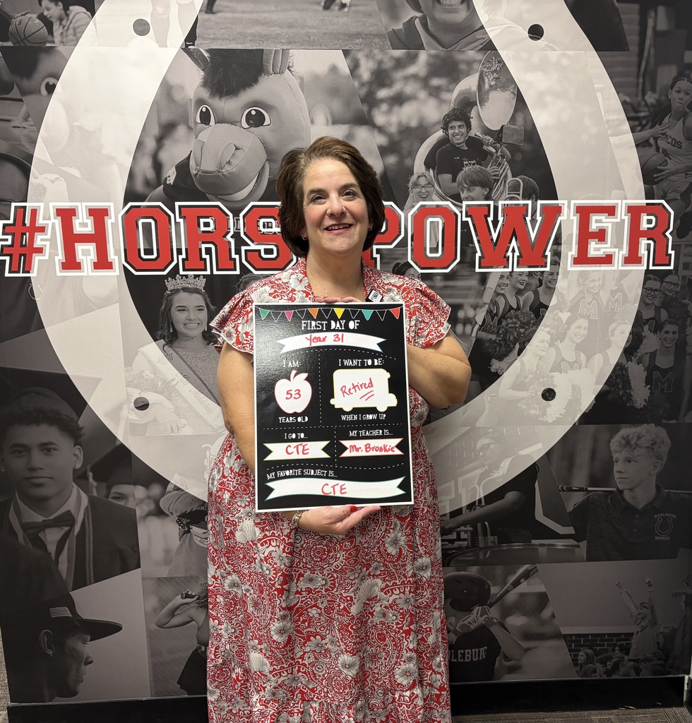 A woman stands in front of a collage, holding a certificate, with a large horseshoe in the background.
