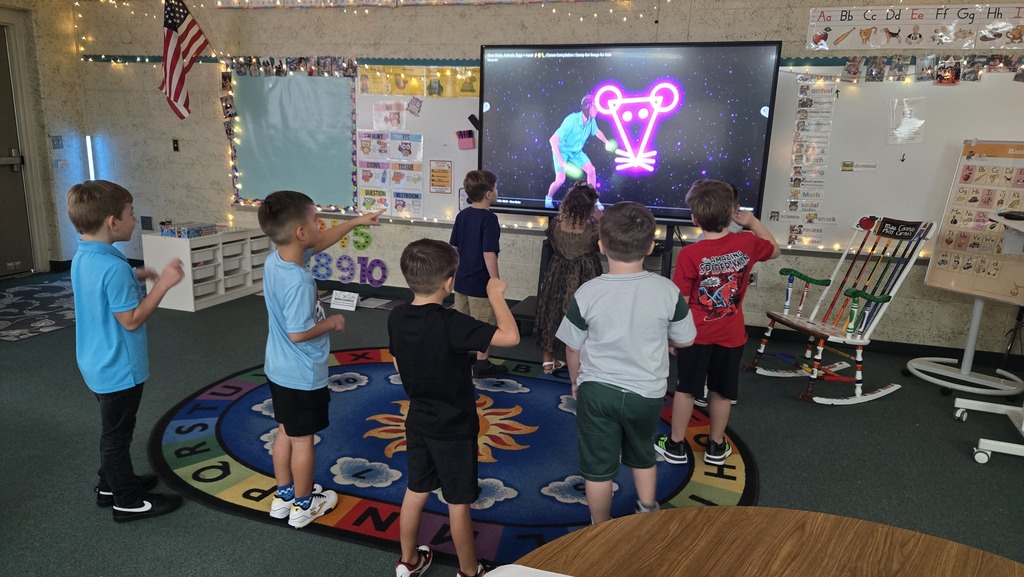 Kids gathered in a classroom with a large screen, likely engaging in a group activity.
