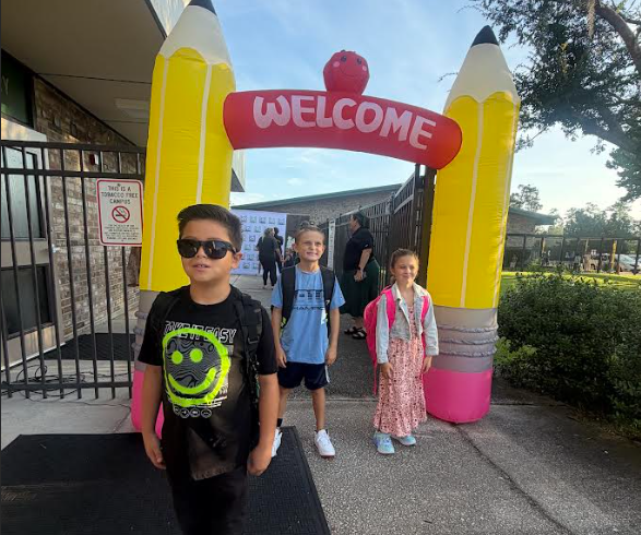 Children standing in front of an inflatable arch with the words "WELCOME" at the top.