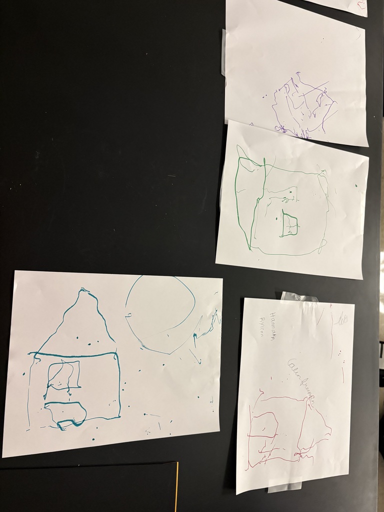 Multiple sheets of paper are pinned on a black background. Each sheet has a simple drawing of a house.