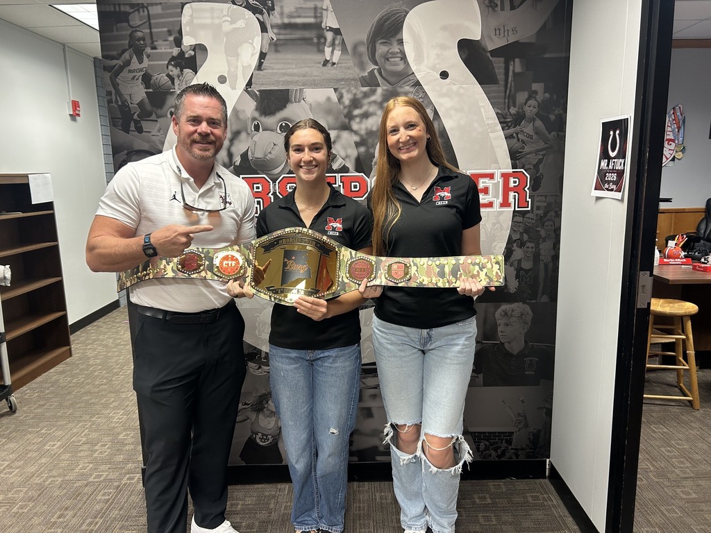 Three people stand next to each other in an office, holding a wide belt. One holds it at the ends.