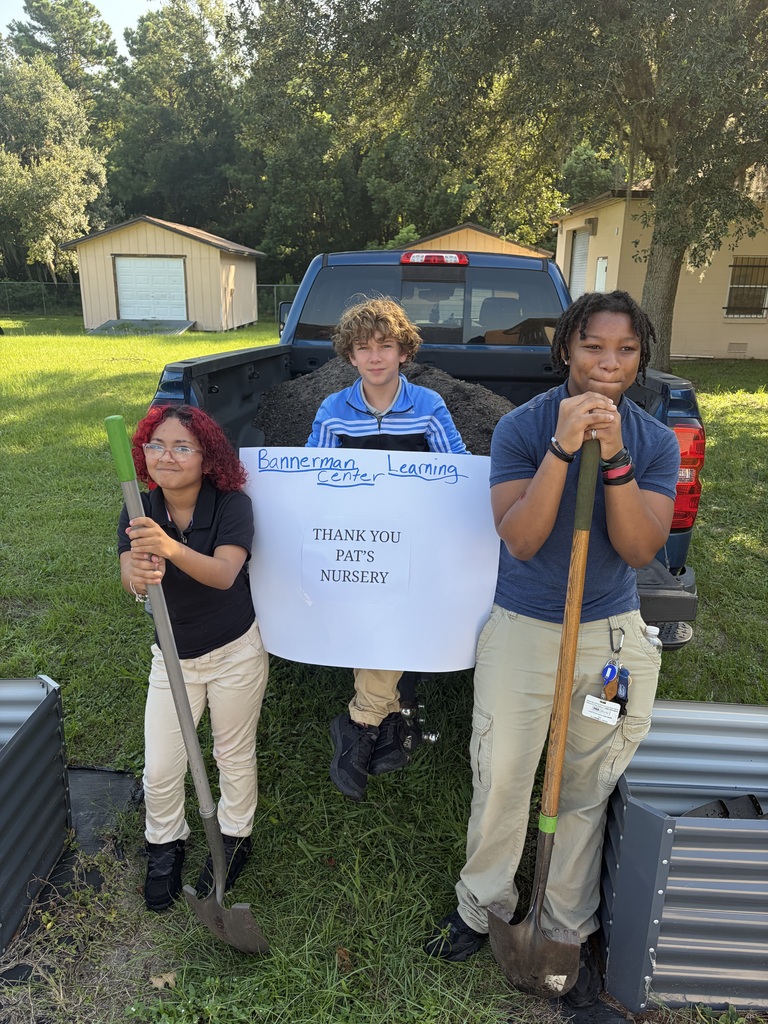 Students with a banner thanking Pats Nursery for donating soil for garden beds.