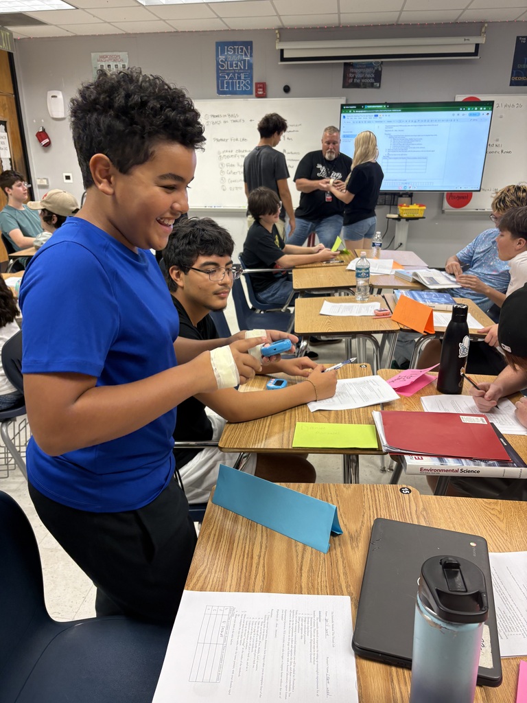 A classroom with students seated at desks, one student in a blue shirt works at a desk.