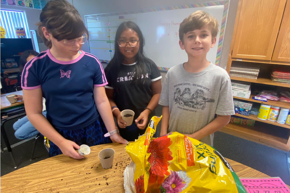 students smiling with soil on a table