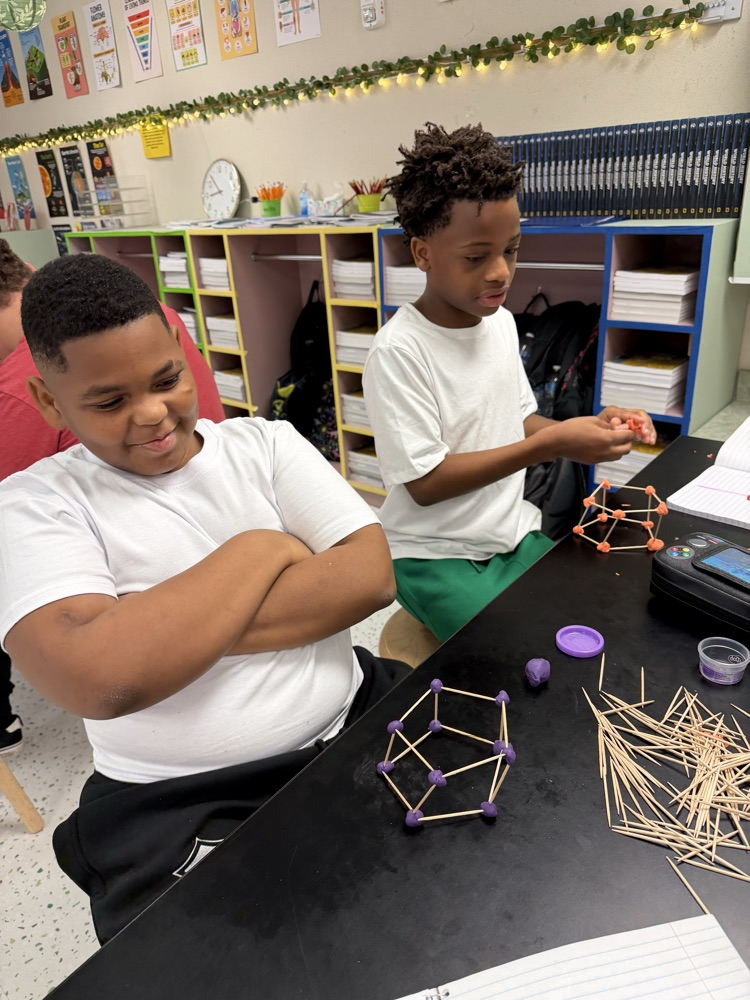 Students in their Science class working on their challenge of creating shapes using popsicle sticks and Play-Doh