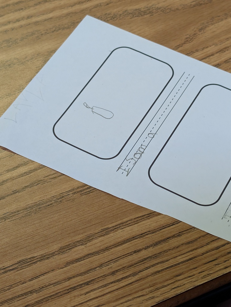 White sheet of paper with two rectangles and a small curve line on a wooden table.