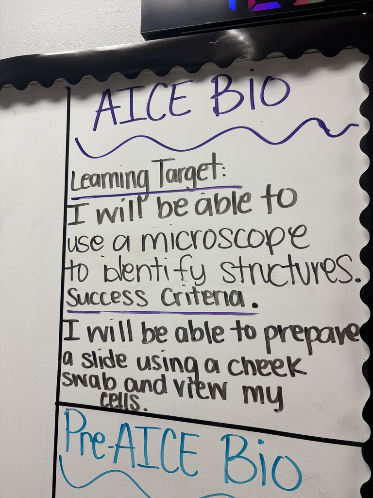 Whiteboard with black border displays educational content. "ALICE BIO" at top, followed by a learning target: "I will be able to use a microscope to identify structures."