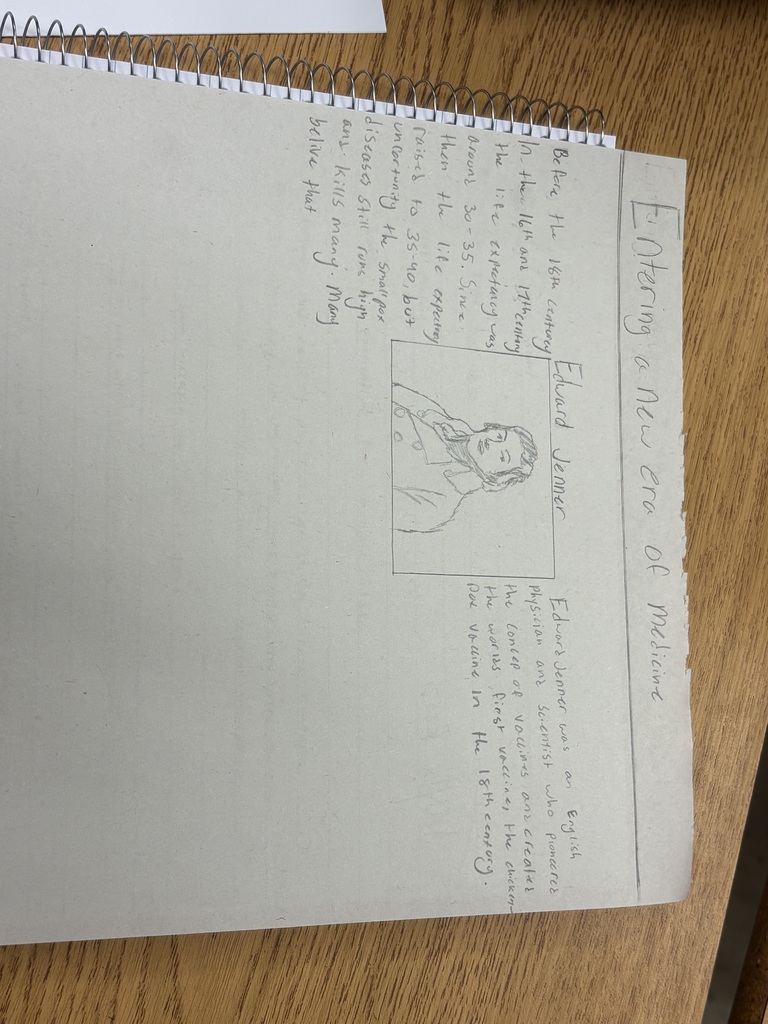 A spiral-bound notebook is open to a page with text and a drawing of a person.