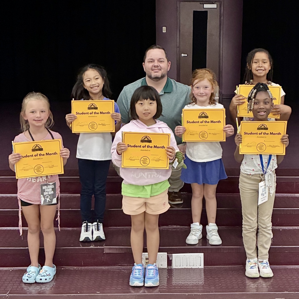 A group of students holding certificates stands on stairs, with Principal Martin at the back.