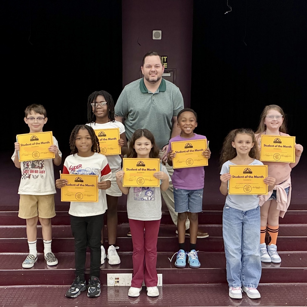 A group of students holding certificates stands on stairs, with Principal Martin at the back.