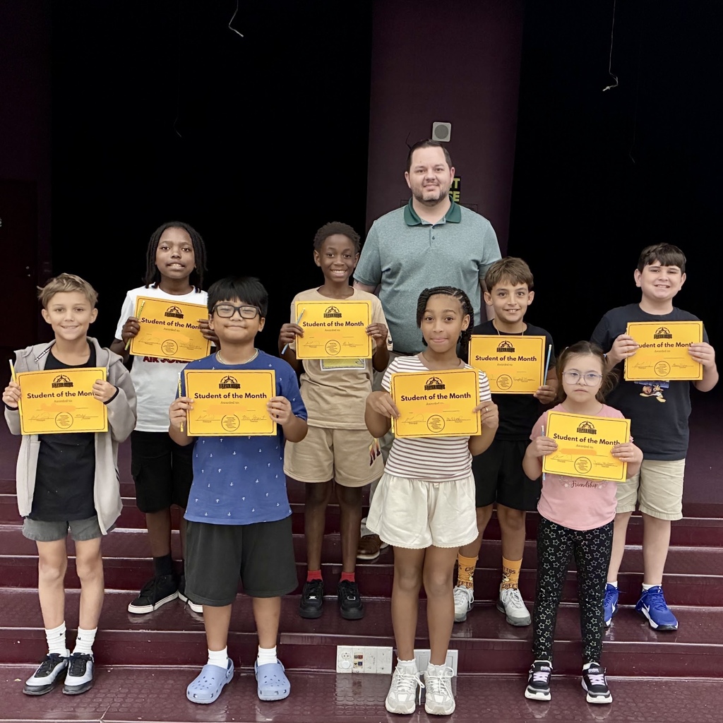 A group of students holding certificates stands on stairs, with Principal Martin at the back.