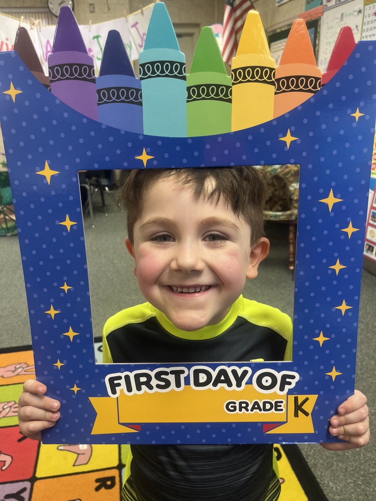 A boy in a yellow and black shirt holds a colorful frame with a smile on his face.