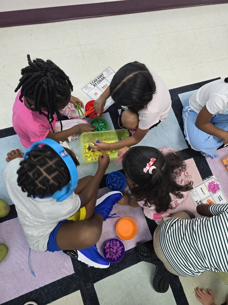 Four children sit on the floor, engaging in an activity with colorful beads. Two wear headphones and one has a headband.