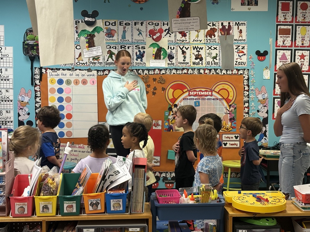 Teenagers are saying the pledge of allegiance with a group of preschool stduents