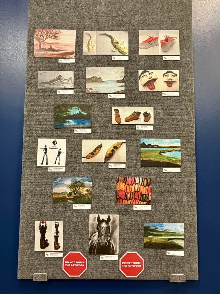 Display of small artwork pieces on a gray felt background. Scenes include landscapes, footwear, a horse, and more.