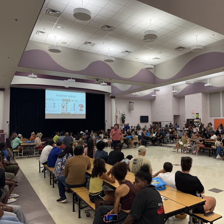 adults and students listening to a presentation from Mr. Martin