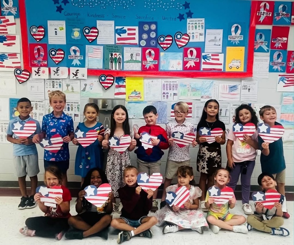 A group of young children are holding heart-shaped American flags. They are smiling and posing for a photo.