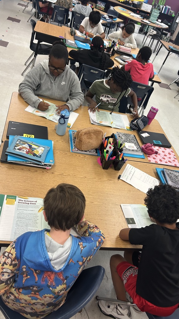 A classroom with students sitting at desks, writing and reading. 