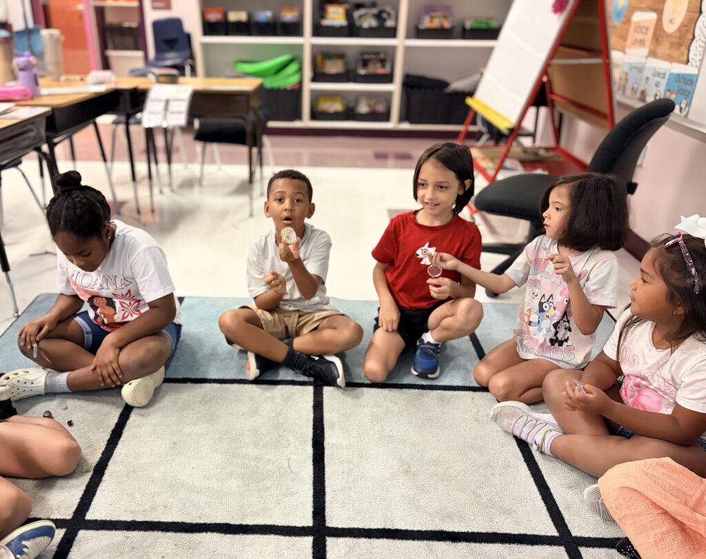 Students using a hand lens to observe rocks.