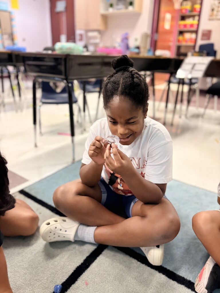 Student using hand lens to observe a rock.