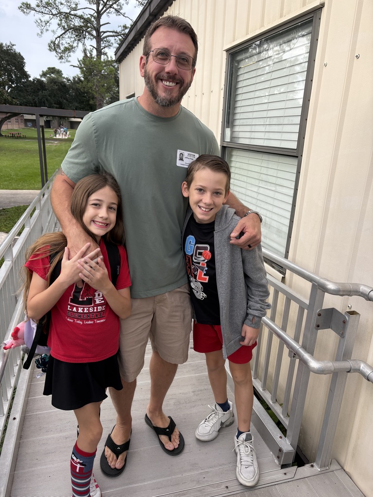 Man and two children standing outside a building. The man has his arm around the shoulders of two kids.