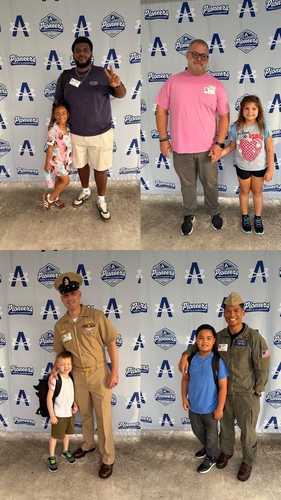 Four adults and four children in various attires, two adults in military uniforms, smiling and standing in front of a wall with blue letters.