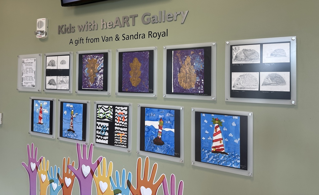 A wall displays framed artworks, including a lighthouse and hearts. Below the artwork, hands painted in various colors.