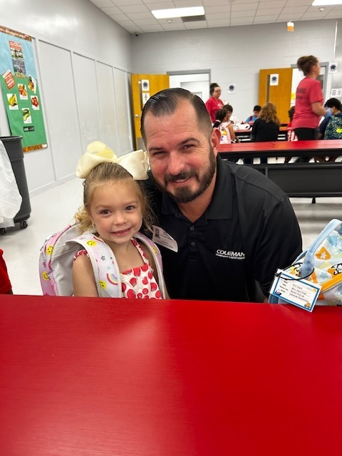 A man with a beard and a girl with a bow in her hair pose at a table.