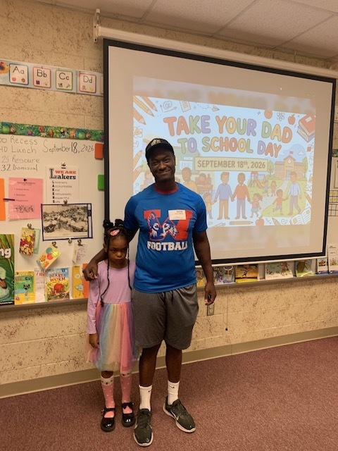 A man and child stand next to each other in front of a projector screen with a colorful graphic.