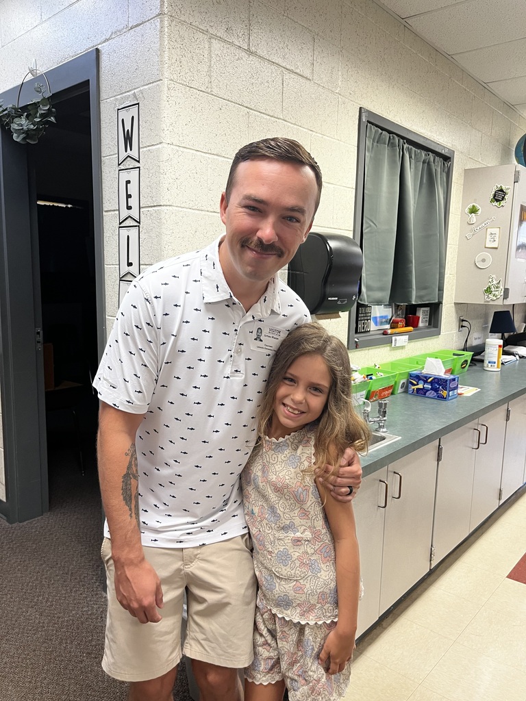 A man and a young girl standing in front of a white counter in a room.