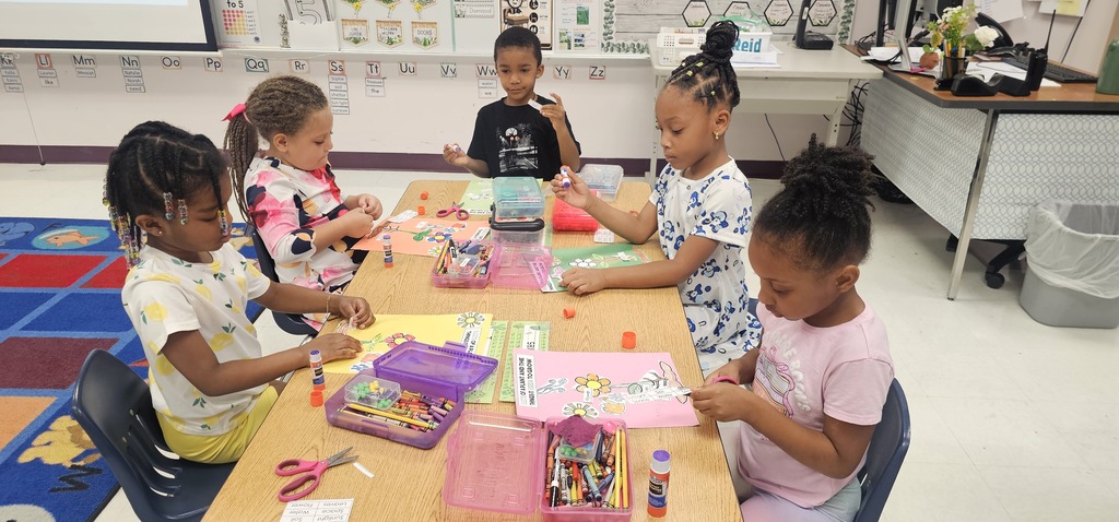 A group of children seated around a table, engaged in a craft activity with various art supplies.