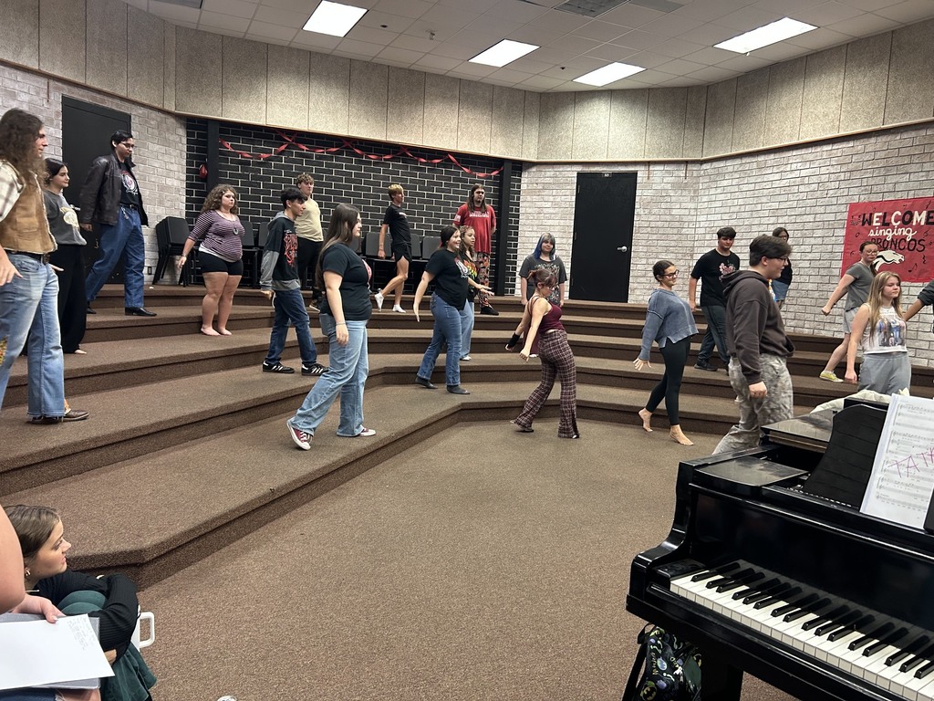 A group of people in a room with brick walls. Some are walking on stairs while others sit or stand.