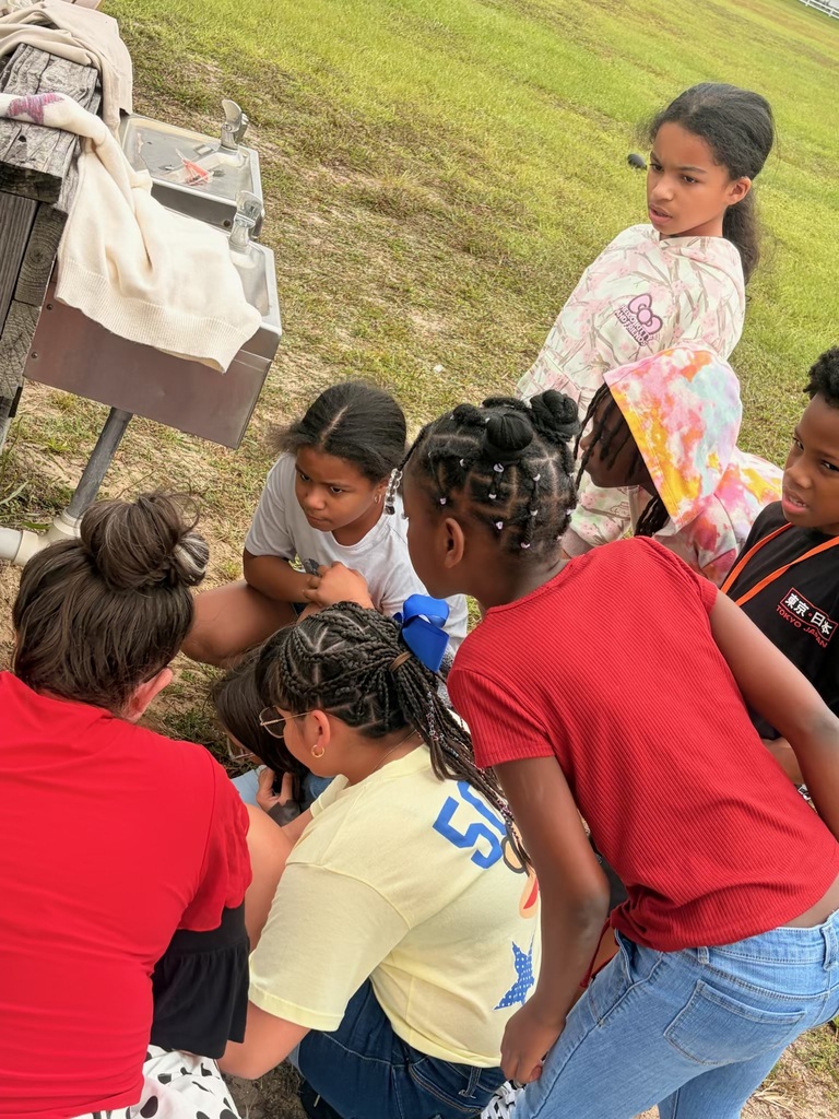 A group of young girls are gathered, with one in a yellow shirt and another in a red shirt.