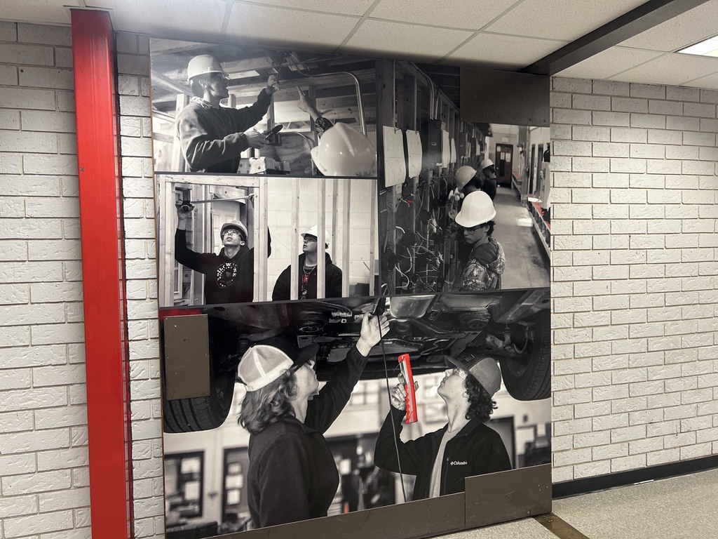 A wall displays a series of black-and-white photos of construction workers, each engaged in various tasks.