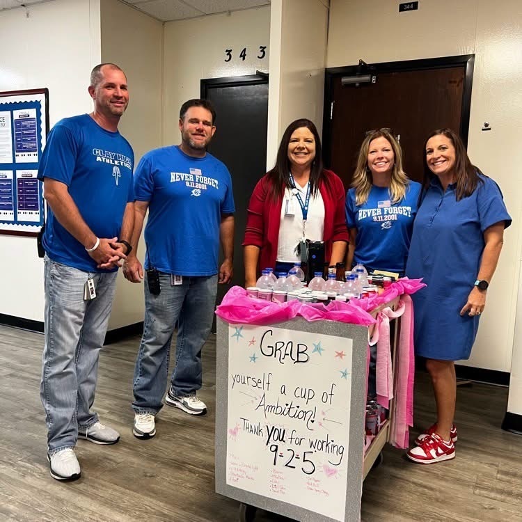 Five people in blue shirts and sneakers stand behind a cart with a sign. The sign reads, "Grab yourself a cup of Appreciation."