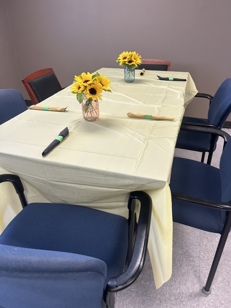 Tables prepared for the CVA recognition luncheon feature light tablecloths, place settings, and bright sunflower centerpieces.