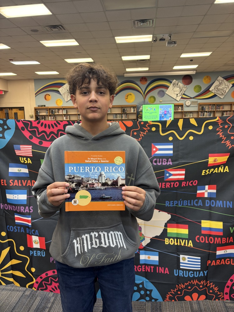 Students holding a book in front of a banner