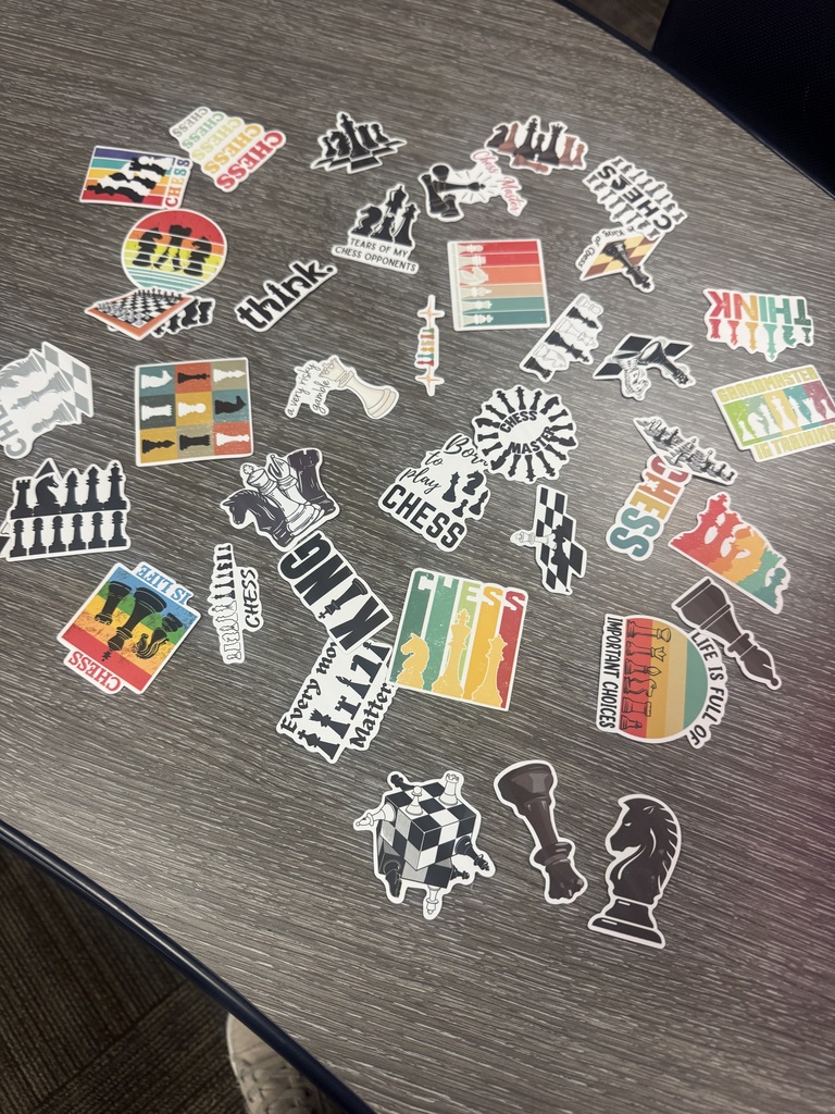 A table covered in chess-themed stickers, including pieces and logos, arranged in a circular pattern.