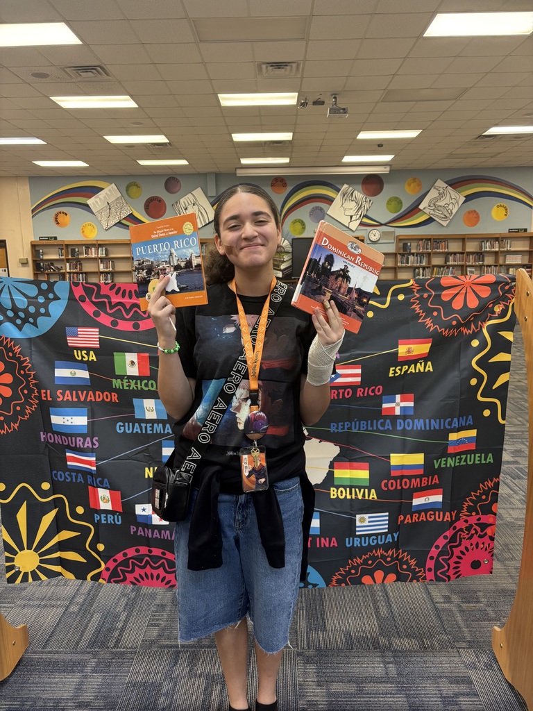 Student holding a book in front of banner