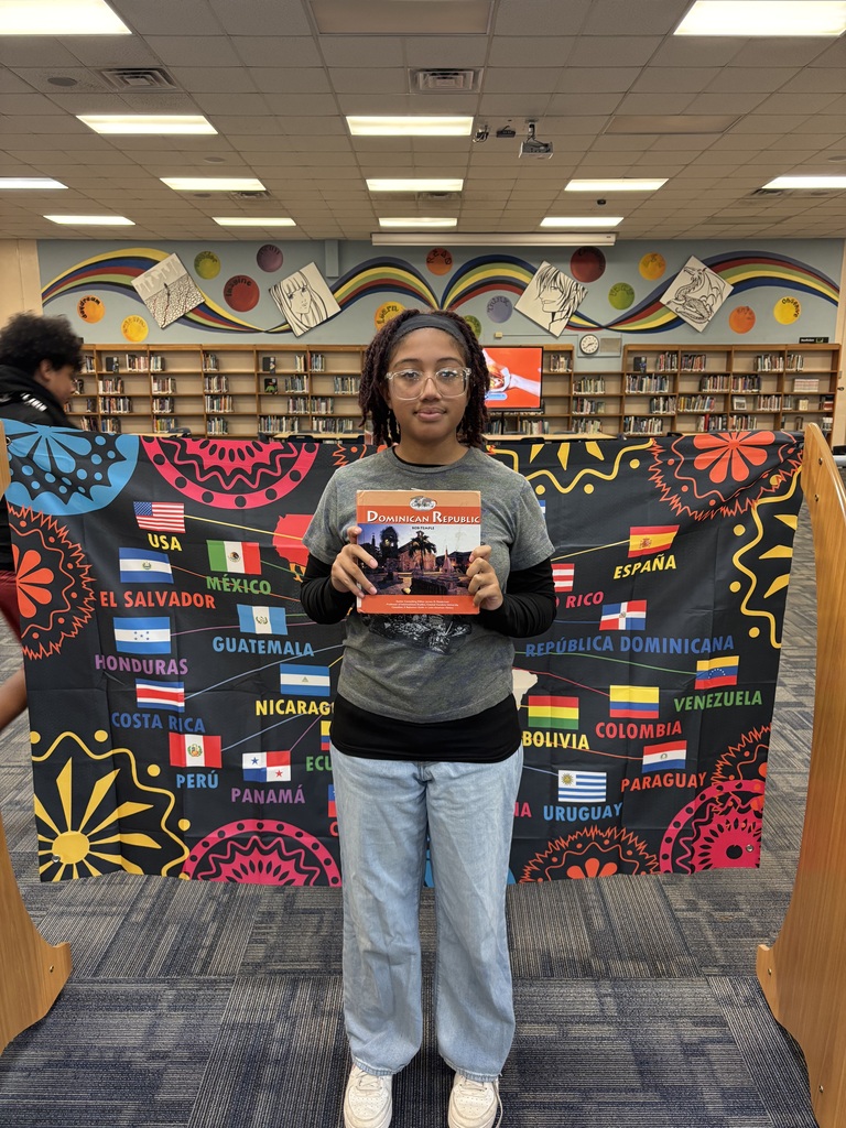 Student holding a book in front of banner