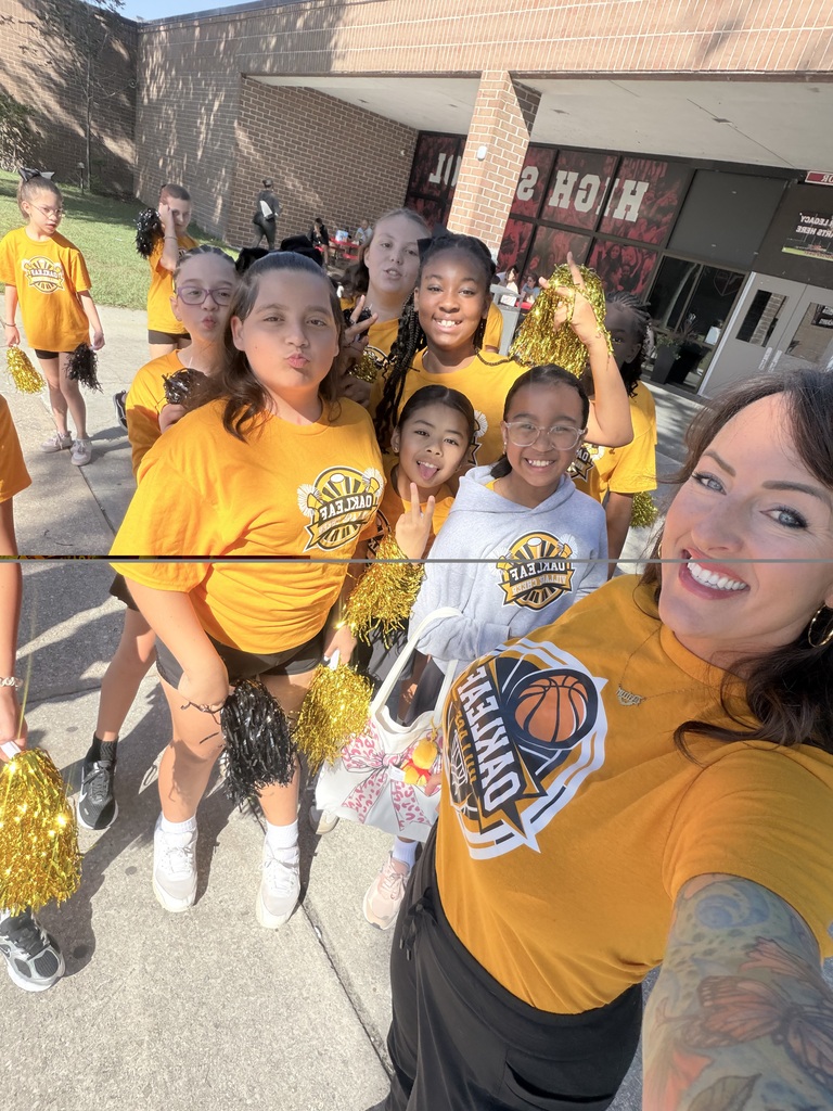 A woman stands with a group of young girls in yellow cheerleading uniforms, smiling at the camera.
