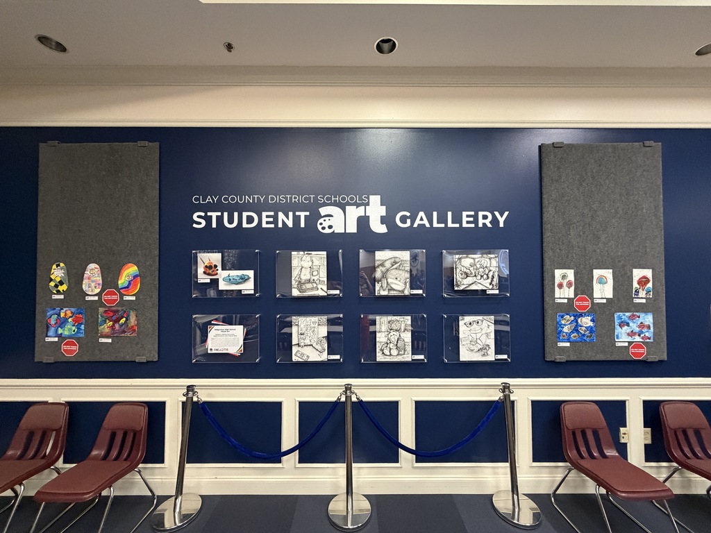 A blue wall displays "Student Art Gallery" with various student artwork, surrounded by a barrier and maroon chairs.