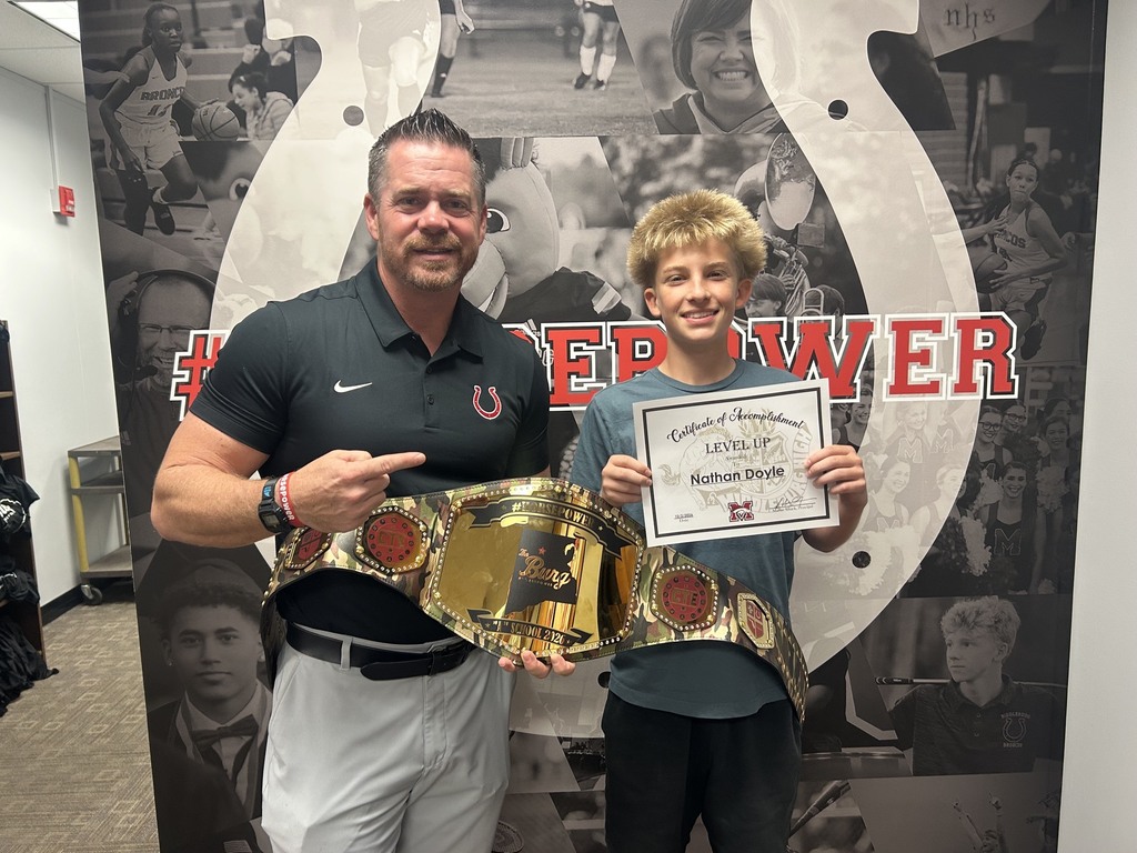 A man and a boy hold a certificate and a belt in front of a collage of sports images.