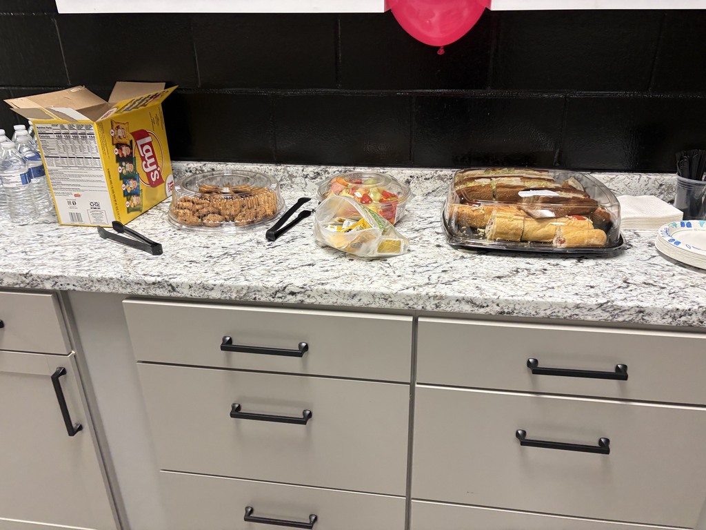 Counter with various food items on it. A red balloon is above. Cabinets and drawers are below.